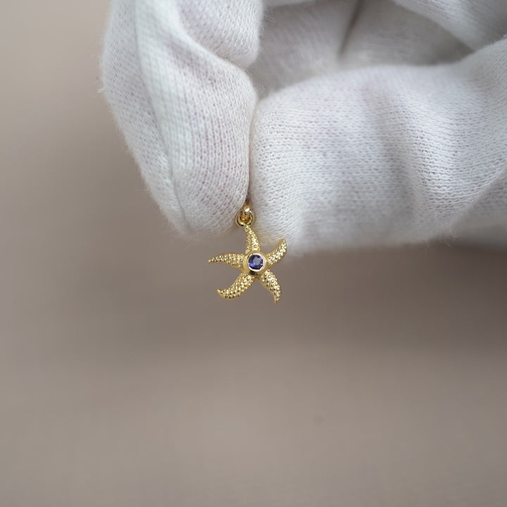 Guldberlock med sjöstjärna och Iolit kristall. Kristallberlock i guld med sjöstjärna och september månadssten Iolit.