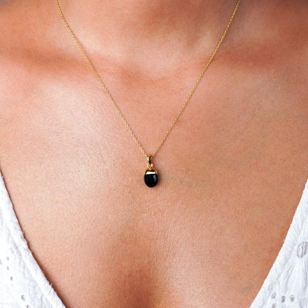Smycke med Onyx i guld att bära som halsband, Kristallsmycke med svart onyx som är juli månadssten.